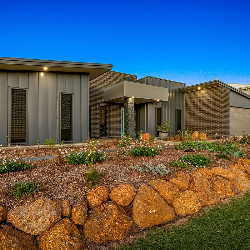 Dark house frontage at dusk with lights on built by Bundaberg home builder
