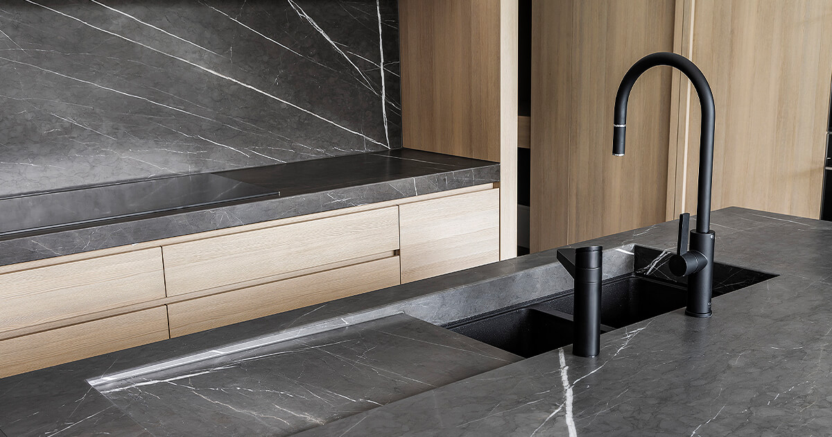 Dark marble and black tap fixtures in kitchen that could add to the home build cost