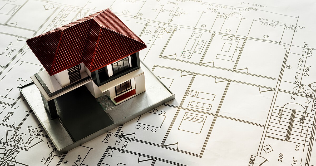 Two story house 3d model sits on printed house plans