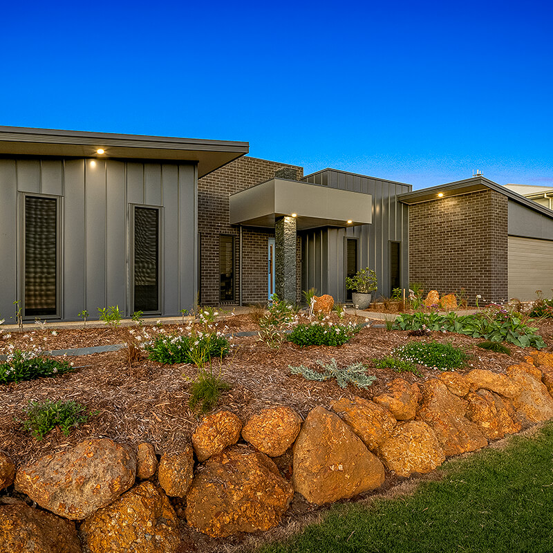 Dark house frontage at dusk with lights on built by Bundaberg home builder
