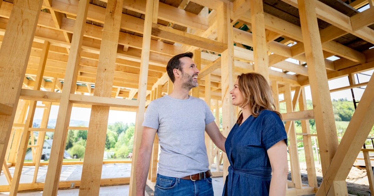 Happy couple building a home with room framing in the background