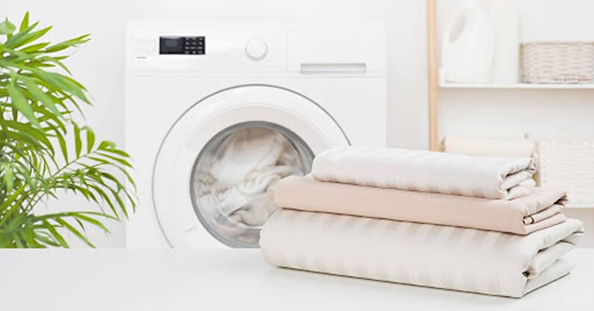 Small laundry room with washing machine and folded sheets