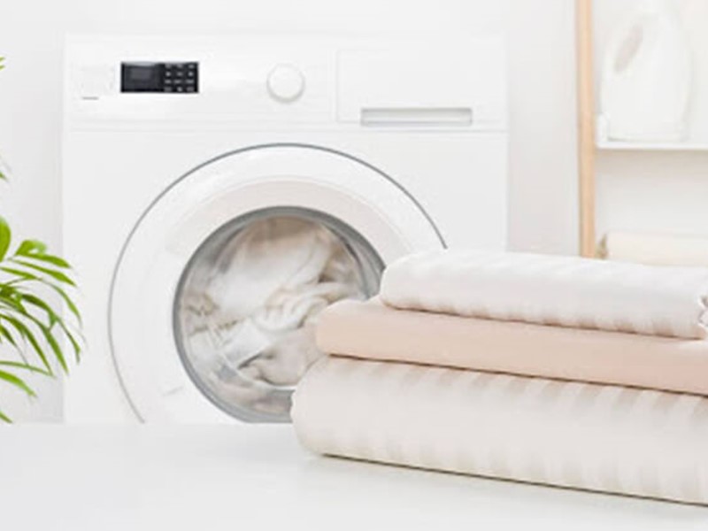 Small laundry room with washing machine and folded sheets